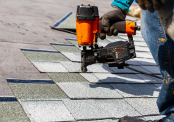 Professional roofer using a nail gun to install shingles on a residential roof, showcasing expert roofing services in Midwest City.