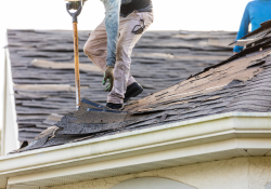 Roofers removing old shingles from a residential roof in Moore, showcasing professional roofing services by Warrior Roofing Solutions.