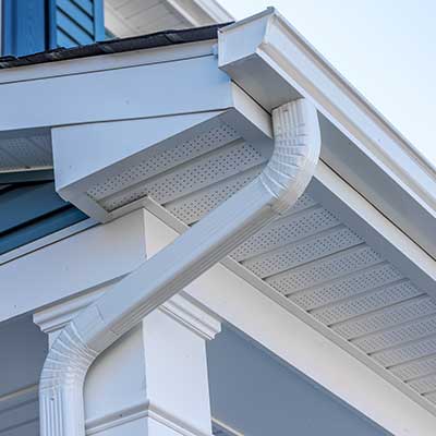 White, k-style seamless gutter system with a downspout, attached to the fascia of a blue home