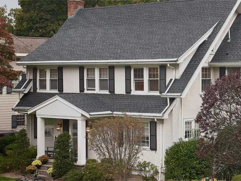 Front view of a typical, mid-class home with dark gray GAF shingles on its roof