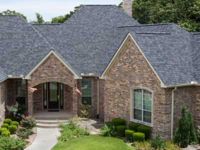 Front view of a large, higher-end home with gray Malarkey shingles on its roof