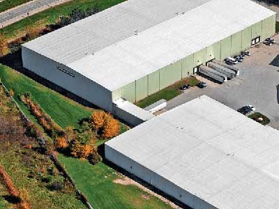 Bird-eye view of two large, commercial warehouses with a white and slightly sloped roof